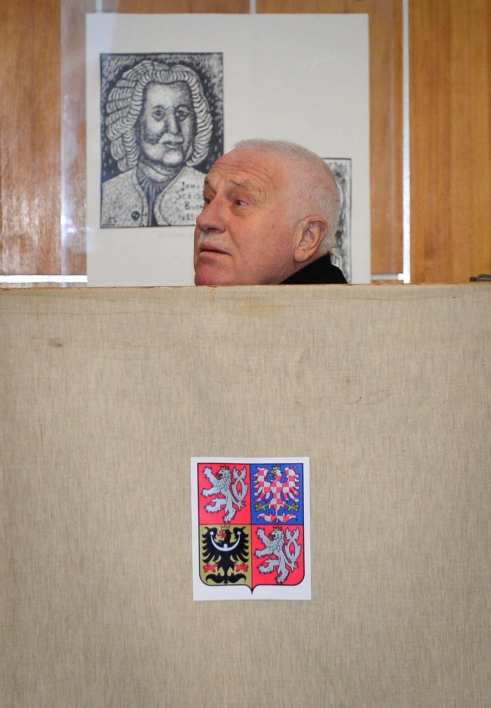 Václav Klaus vykukuje zpoza plenty ve volební místnosti při druhém kole prezidentské volby