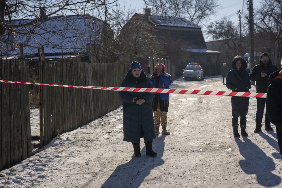 Obyvatelé čekají za policejním kordonem, aby se vrátili do svých domovů po raketovém útoku na předměstí Kyjeva