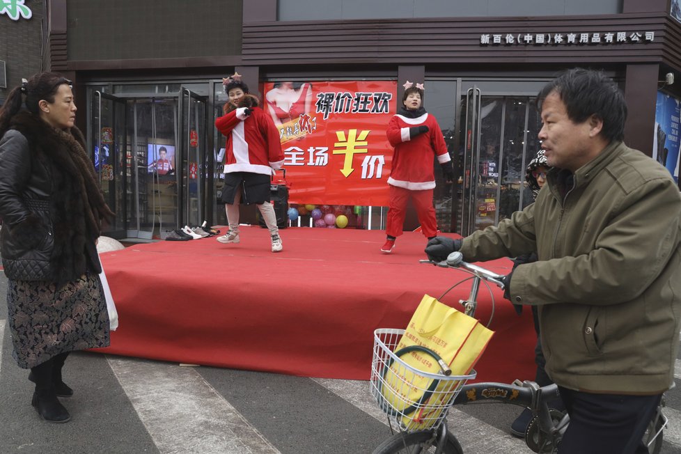 Zaměstnanci se snaží nalákat zákazníky na slevy v čínském obchodě