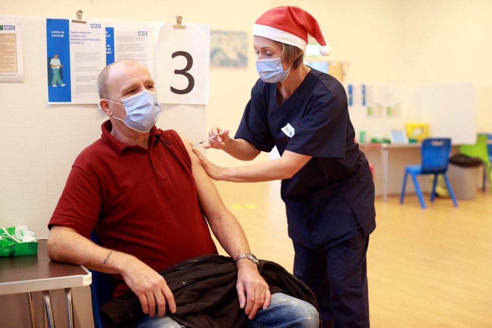Ve Velké Británii si zdravotníci na očkování proti covidu během svátků zvali vánoční čepice (25.12.2021)