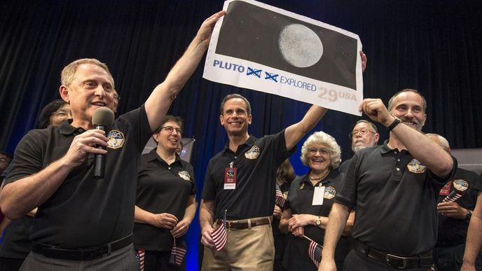 Vědci v NASA drží fotografii Pluta