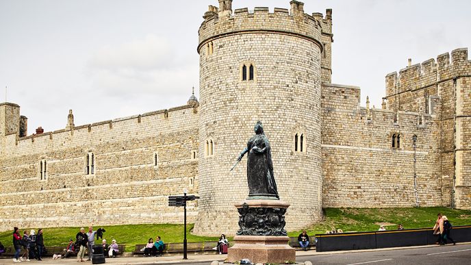 Hrad Windsor je jednou z největších hradebních struktur v Evropě. Před hradbami stojí socha královny Viktorie.