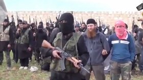 Vpředu má džihádista John alias Mohammed Emwazi proslov, vzadu za ním stojí muž s rudým vousem, Abu Omar al - Shiskani.