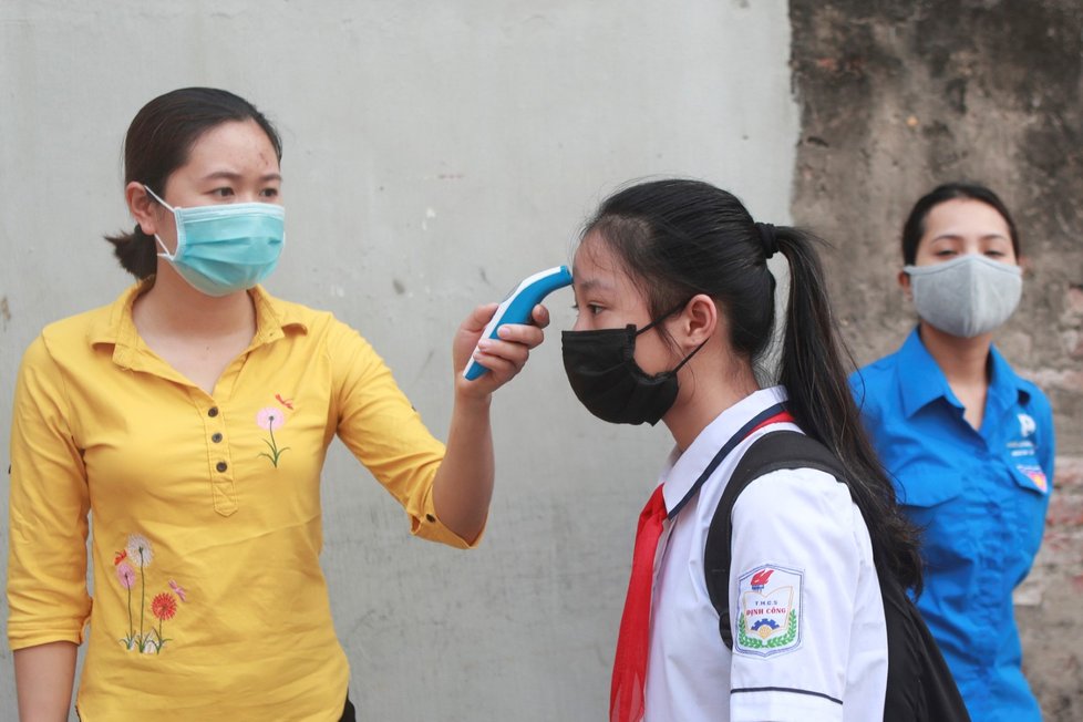 Školáci ve Vietnamu se po třech měsících vrátili do tříd. Čekalo je měření teploty i výuka v rouškách. (4. 5. 2020)