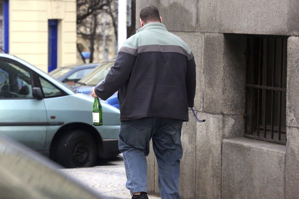 Vrátný jde nalezenou lahev vyhodit do kontejneru na tříděný odpad.