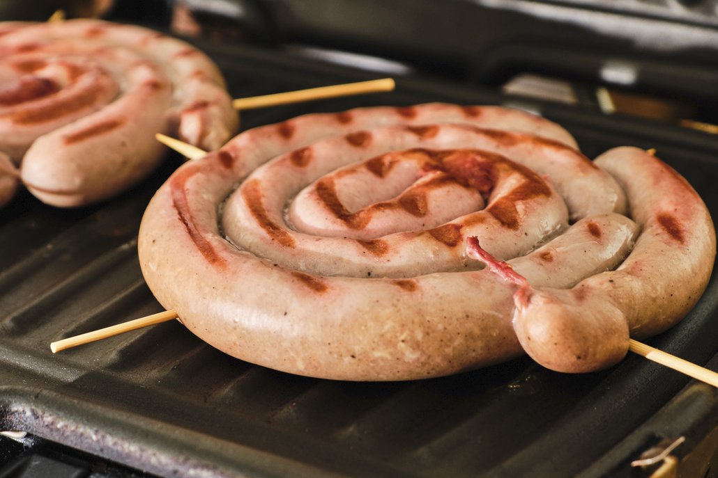 Vinná klobása na pivě se peče smotaná do šneků, zpevněná špejlí v pekáčku s cibulí, nakrájenou slaninou, česnekem, rajským protlakem a pivem.