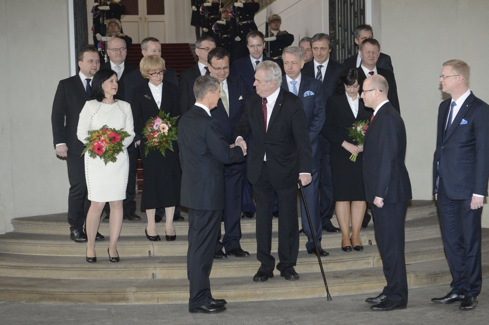 Společné foto nového kabinetu ministrů s prezidentem. Faktem je, že Věra Jourová bílými vlněnými šaty sestavu rozsvítila. Otázkou je, zda byly dobrou volbou pro její plnoštíhlou postavu a se stejným otazníkem lze vnímat jejich zdobení umocněné černým páskem, jenž skrývá kytice. Paní Válková zvolila dobrý kostým v délce midi sukně, ale závěs se srdíčkem přes košili s příliš velkými perleťovými knoflíky jí body nepřidá. Kolegyně Marksová – Tominová si zapnula sako a symbolizovala nudu, jež neprovokuje.