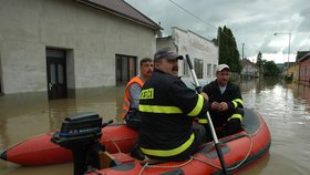 Hasiči obráží vesnici na člunech a zjišťují, jestli někdo z obyvatel něco nepotřebuje.