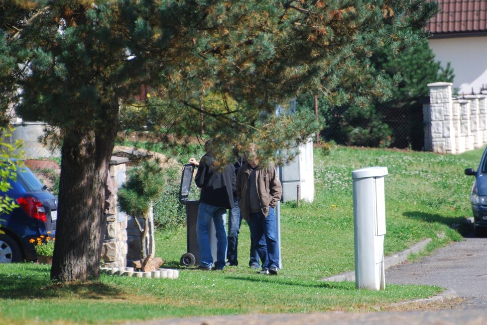 Kriminalisté na místě tragédie prohlížejí obsah popelnice před domem