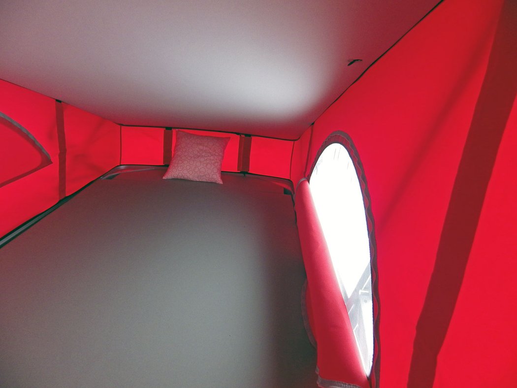 Červená plachtová nástavba nabízí dvě otvírací okénka s moskytiérou