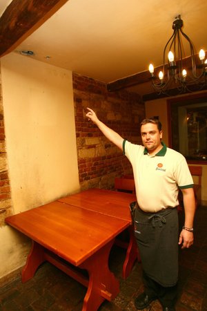 Pracovník restaurace ukazuje stopy po granátu