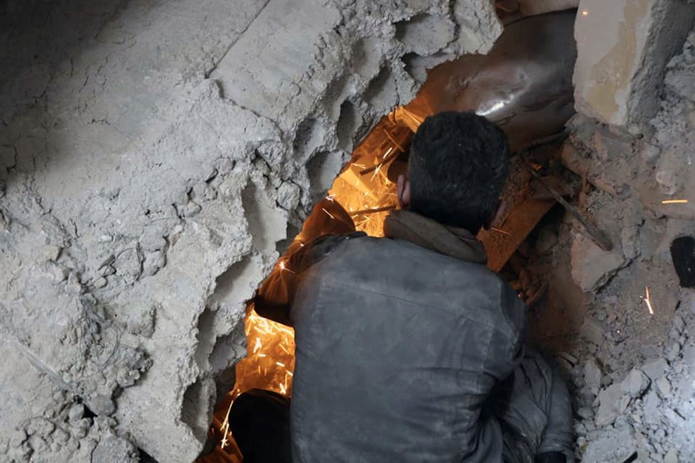 Syrská civilní obrana, tzv. „bílé helmy,“ prohledává trosky zřícených budov po bombardování.