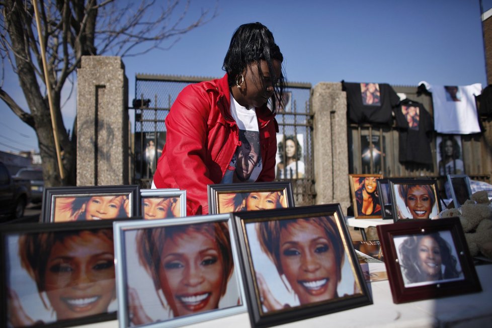 Žena aranžuje fotografie Whitney, které si mohou fanoušci zakoupit