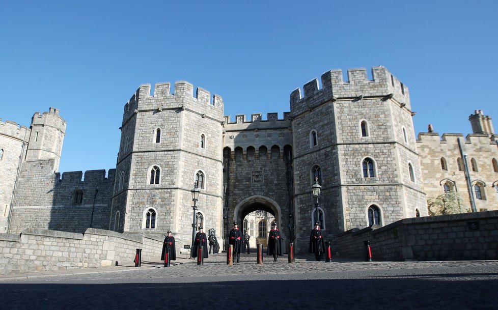 Dozorci stojí před hradem Windsor.