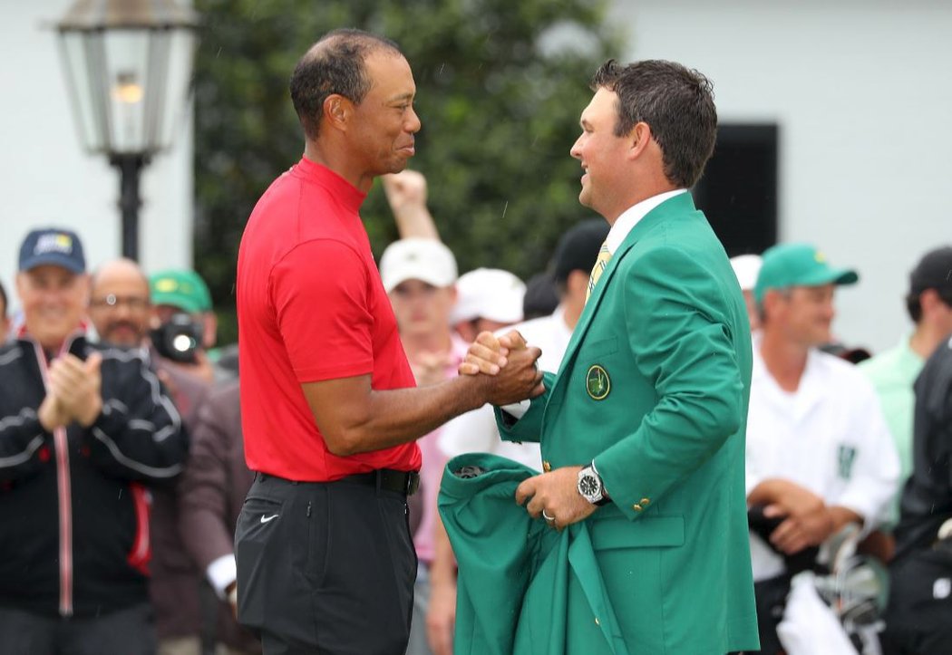 Loňský vítěz Masters Patrick Reed předa mistrovi mistrů Woodsovi tradiční zelené sako...