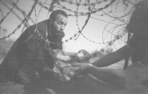 Vítězné World Press Photo: Migranti si předávají kojence skrz ostnaté dráty