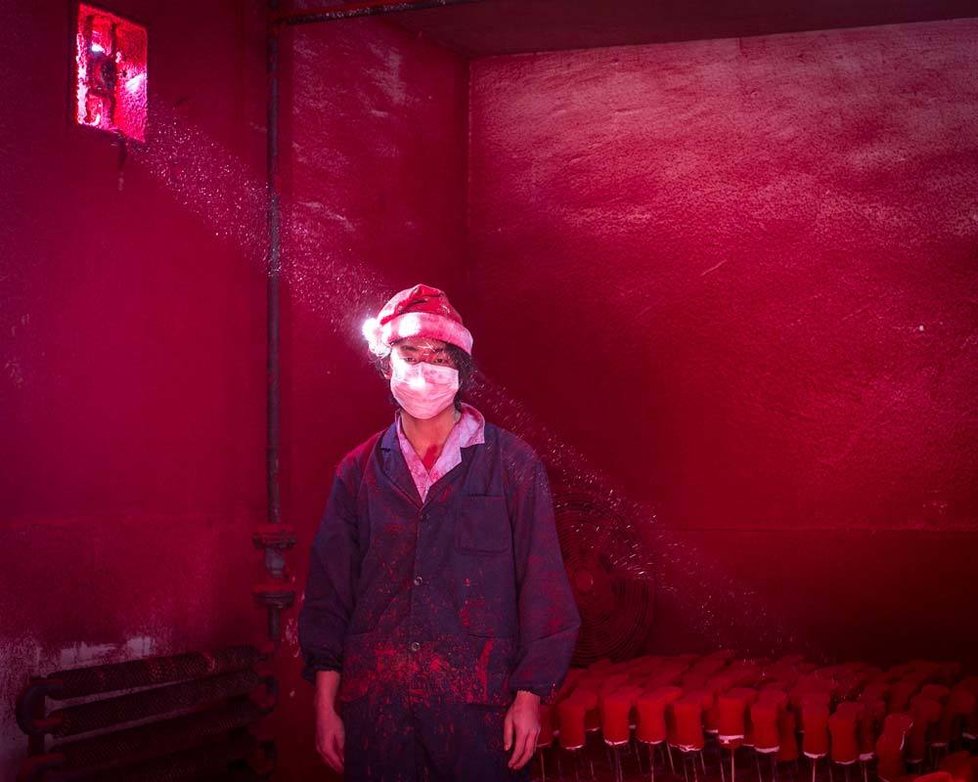 2. cena v kategorii Současné problémy, jednotlivý snímek. Autor: Ronghui Chen (Čína). Wei (19 let) pracuje v továrně v Yiwu ve východní Číně, kde obaluje v červeném prášku polystyrenové sněhové vločky. Na hlavě má vánoční čepici, aby si chránil vlasy, a za den spotřebuje více než šest roušek na obličej.