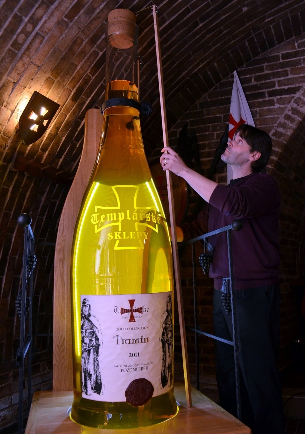 Komisař Michal Jurečka měří výšku obří lahve, do níž se vejde 200 litrů vína vinařů z Čejkovic.
