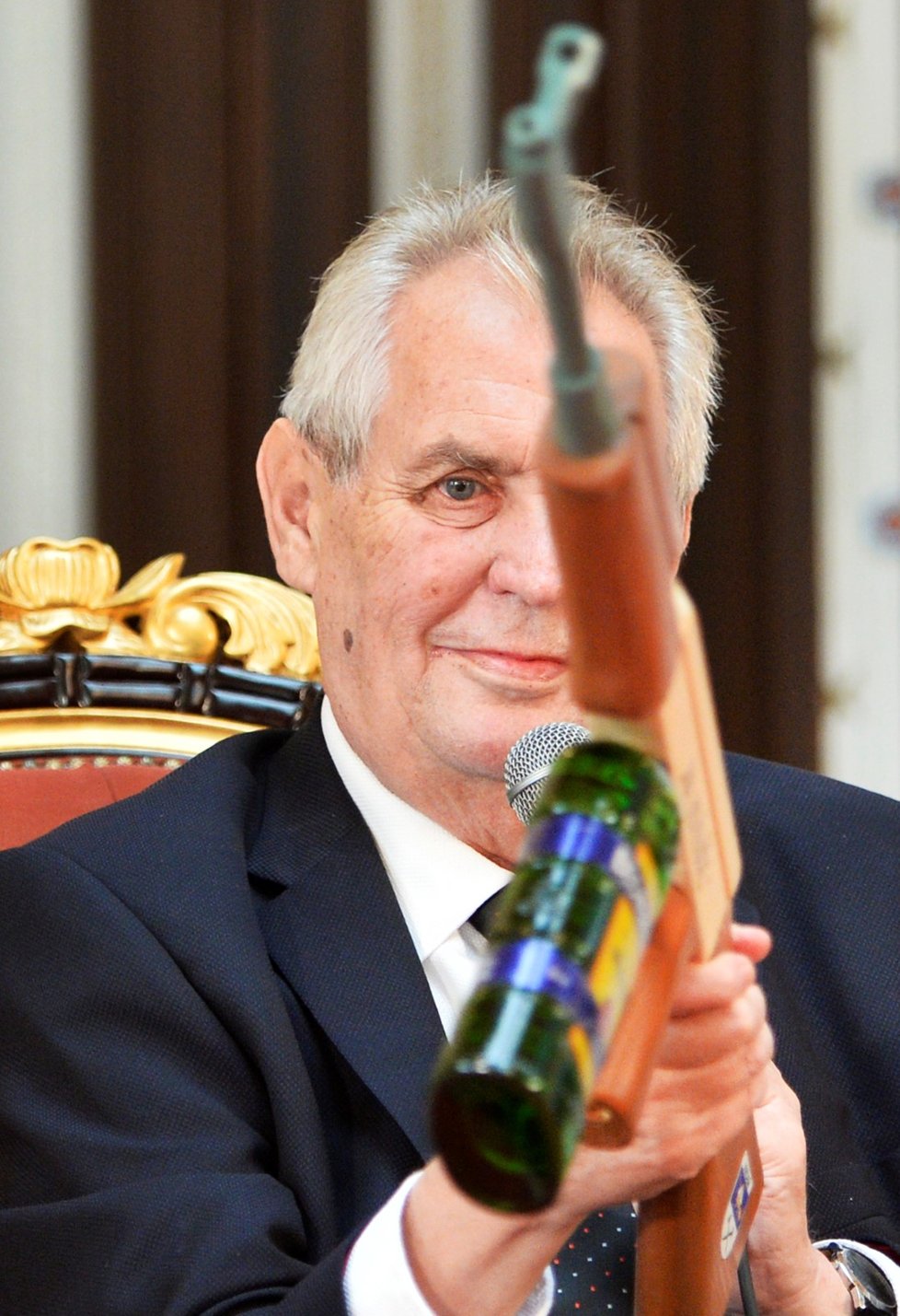 Prezident Miloš Zeman dostal na závěr návštěvy Plzeňského kraje jako dárek maketu slavného samopalu kalašnikov „na novináře“, místo zásobníku má láhev Becherovky.