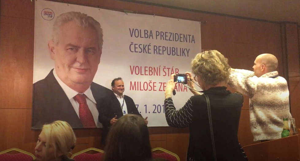 Příznivci Miloše Zemana se fotí u plakátu s jeho podobiznou.