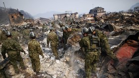 Japonští záchranáři pátrají v sutinách domů.