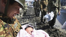 Člen japonských ozbrojených sil s úsměvem na tváři a zachráněnou čtyřměsíční holčičku v náručí v Ishimaki na severu Japonska.
