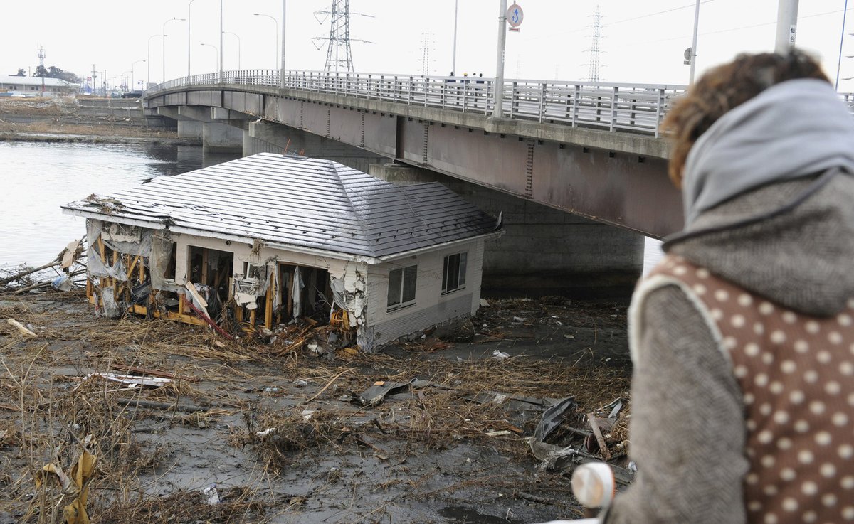 Sílu tsunami dokazuje tento snímek: jeden z domů zapasoval příliv přímo pod most.