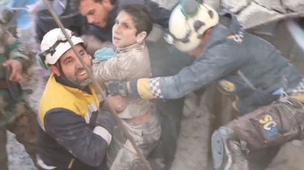 Záchranáři v syrském městě Jandaris vytahují zpod sutin přeživší dítě
