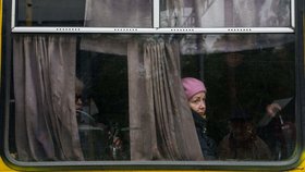 Žena vyhlíží z okna autobusu během lokálního příměří spojeného s evakuací obyvatel Olešek v Chersonské oblasti na Ukrajině (27. 10. 2026)