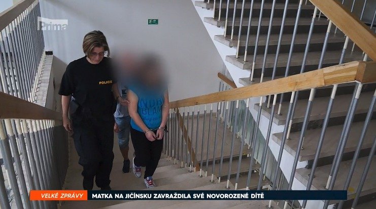 Mladá žena na cestě k soudu s policejní eskortou