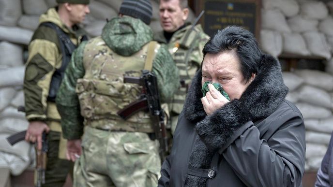 Žena prochází kolem ozbrojených separatistů v Doněcku
