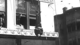 Harry Houdini unikal ze svěrací kazajky zavěčený v ulicích hlavou dolů.