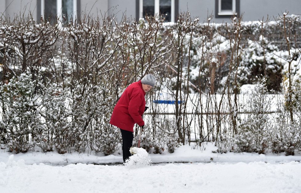 Žena odklízí sníh z chodníku na sídlišti Obeciny ve Zlíně (13. 1. 2021)